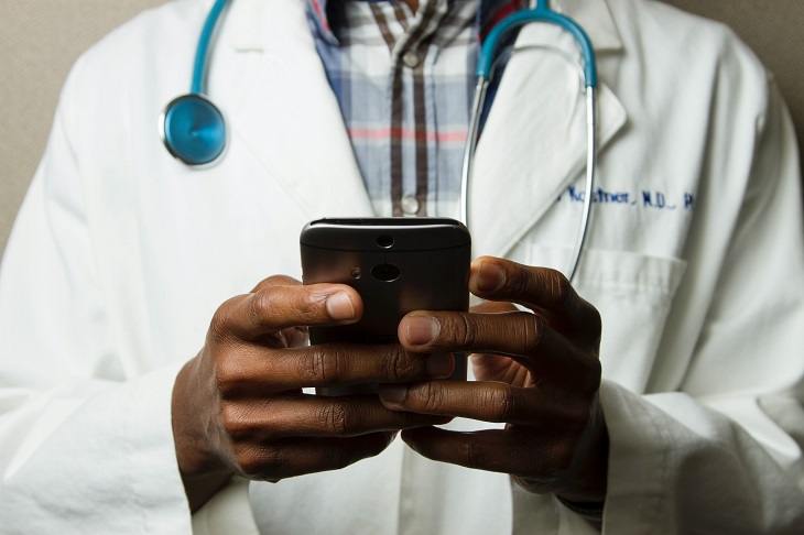 doctor in lab coat using phone for telemedicine